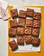 © Jennifer Causey - Homemade cut brownies on an orange cutting board with spatula