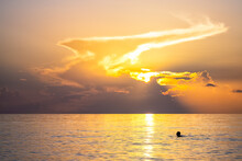 Hollywood Beach In Miami, Florida Morning Sunrise Sun Behind Sky Clouds With Reflection Path, Person People Swimming In Calm Still Landscape Water