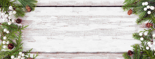 Aufkleber - Winter double border with evergreen branches, white berries and pine cones. Above view on a rustic white wood banner background with copy space.