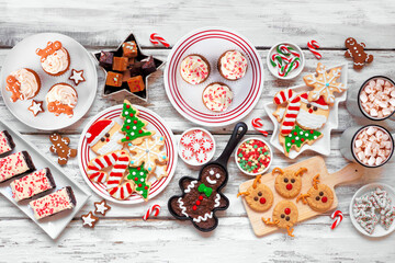 Wall Mural - Cute Christmas sweets and cookie table scene. Top view over a rustic white wood background. Fun holiday baking concept.