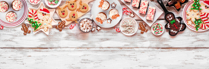 Wall Mural - Cute Christmas sweets and cookie top border. Above view over a rustic white wood banner background with copy space. Fun holiday baking concept.