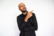 © KAMPUS - Portrait of serious young man pointing at ads. Confused Latin American male model with bald head and beard in black shirt looking away, showing direction with finger. Advertisement concept