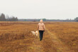 © Александр Поташев - A woman walks with a dog, a golden retriever in the autumn forest.