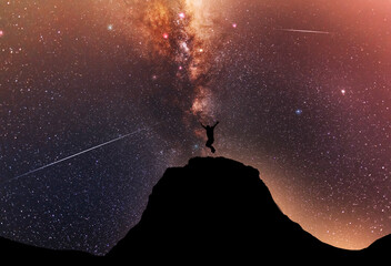 Wall Mural - hiker silhouette jumping on the hill, behind them fantastic beautiful night sky with milky way galax