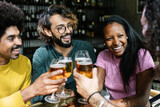 Fototapeta Londyn - Group of diverse friends enjoying weekend together cheering with beers at brewery bar - International friendship concept