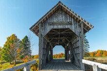 Scenic Shot Of The Wooden AM Foster Bridge Surrounded By Autumn Foliage And Blue Sky
