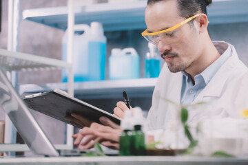 Wall Mural - research man is standing and making notes on a pen in his notebook in a laboratory.