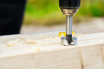 Wall Mural - Carpenter drilling holes in the wood beam. wooden frame domestic house building. drilling a hole with a handheld drill