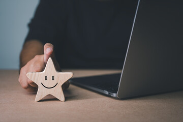 customer service The best business scoring experience Satisfaction Survey Concept A businessman's hand selects a smiling face on a star-shaped wooden block. 5 star satisfaction