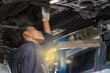 © Jack Tamrong - African black mechanic woman working underneath car in auto garage repair shop, Car Mechanic Concept