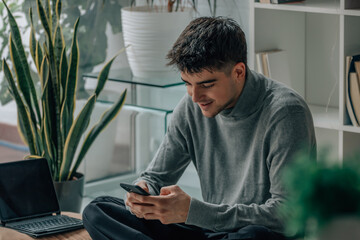 Wall Mural - young man or teenager at home with mobile phone