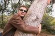 Adult man hugging a tree.