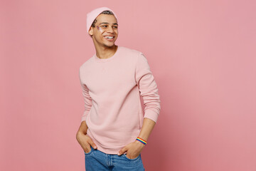 Wall Mural - Side view young happy smiling fun gay man wear sweatshirt hat look aside on workspace area mock up isolated on plain pastel light pink color background studio portrait. Lifestyle lgbtq pride concept.