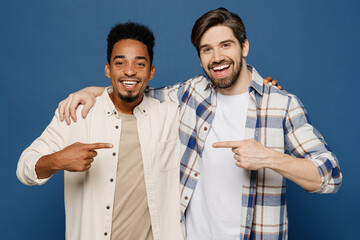 Wall Mural - Young two friends fun cool men wear white casual shirts together looking camera put hand on shoulder point finger on each other isolated plain dark royal navy blue background People lifestyle concept