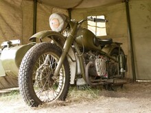 A Military Motorcycle With A Sidecar Under An Awning. Military Camouflage Motor Vehicles Of The Second World War.