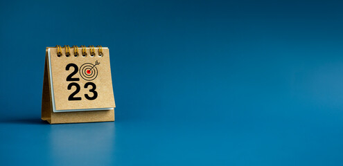 Poster - happy new year 2023 banner background. 2023 numbers year with target icon on beige small desk calend