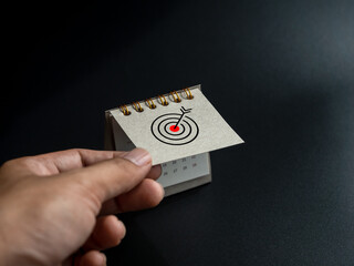Poster - start new goals in new year concept. close-up target icon on small grey desk calendar cover opens by