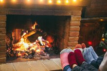 Happy Family Wearing Warm Socks In Front Of Cozy Fireplace During Christmas Time - Focus On Right Socks