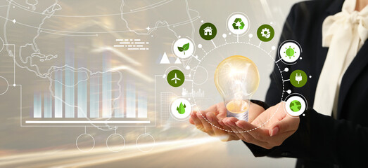 Businesswoman using virtual screen with light bulb and different icons. Green technology concept