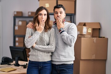 Sticker - Young hispanic couple working at small business ecommerce covering mouth with hand, shocked and afraid for mistake. surprised expression