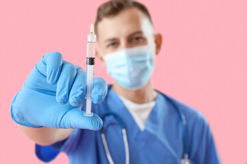 Poster - Male doctor in medical mask with syringe on pink background, closeup