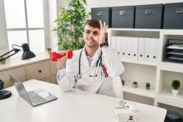 Sticker - Young hispanic doctor man holding dumbbells smiling happy doing ok sign with hand on eye looking through fingers