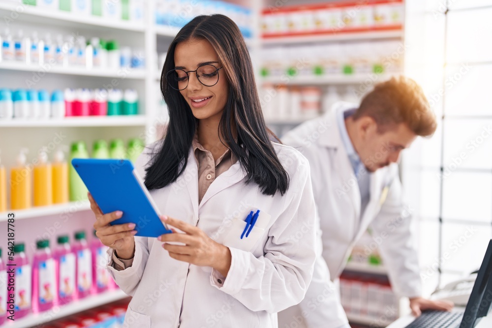 Pharmacist Multitasking Man and woman pharmacists using touchpad and computer working at ...