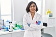 © Krakenimages.com - Young latin woman wearing scientist uniform standing with arms crossed gesture at laboratory