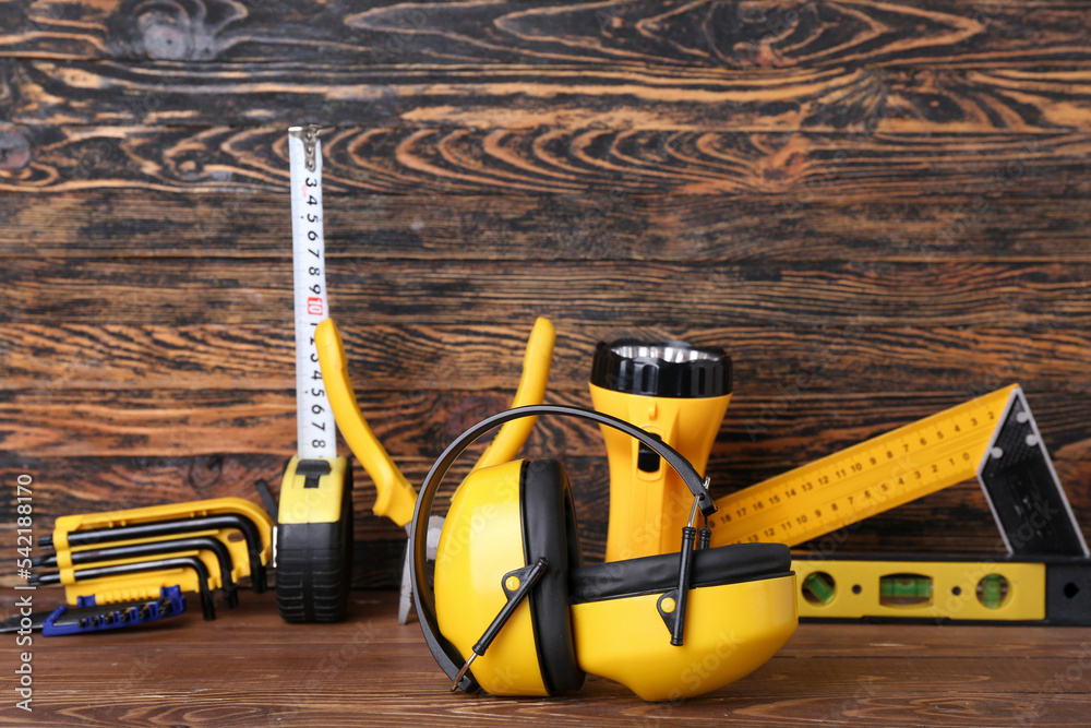 Hearing protectors with builder's tools on dark wooden background