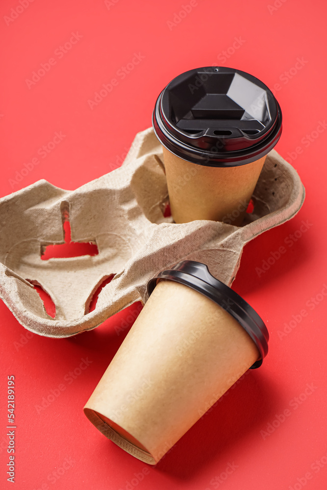 Holder with paper cups on red background