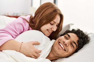 Wall Mural - Young couple smiling happy and hugging lying on the bed at bedroom.