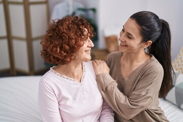 Poster - Two women mother and daughter hugging each other sitting on bed