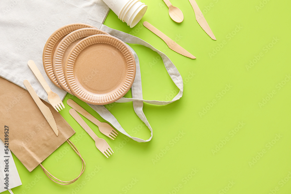 Different bags and Eco tableware on green background