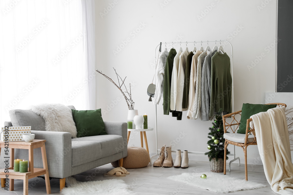 Stylish interior of dressing room with rack and warm sweaters