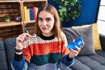 Canvas Print - Young hispanic girl holding invisible aligner orthodontic relaxed with serious expression on face. simple and natural looking at the camera.