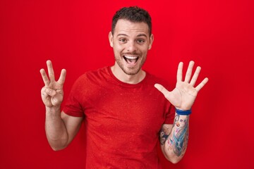 Poster - Young hispanic man standing over red background showing and pointing up with fingers number eight while smiling confident and happy.