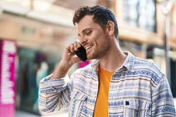 Wall Mural - Young hispanic man smiling confident talking on the smartphone at street