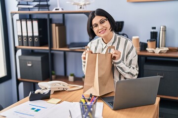 Wall Mural - Young chinese woman business worker holding take away paper bag at office