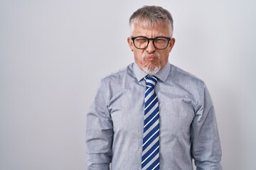 Poster - Hispanic business man with grey hair wearing glasses puffing cheeks with funny face. mouth inflated with air, crazy expression.