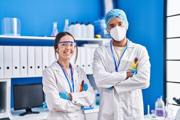 Wall Mural - Man and woman scientists smiling confident standing with arms crossed gesture at laboratory