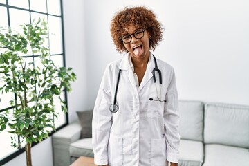 Sticker - Young african american woman wearing doctor uniform and stethoscope sticking tongue out happy with funny expression. emotion concept.