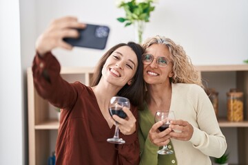 Wall Mural - Two women mother and daughter drinking wine make selfie by smartphone at home