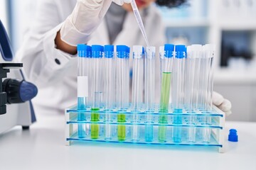 Poster - Young middle east woman scientist pouring liquid on test tubes at laboratory