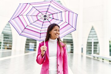 Canvas Print - Young latin woman smiling confident holding umbrella standing at street