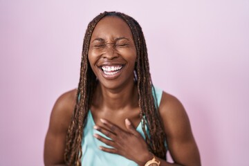 Wall Mural - African american woman standing over pink background smiling and laughing hard out loud because funny crazy joke with hands on body.