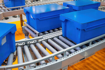 Poster - Warehouse conveyor. Automatic conveying line. Blue boxes on conveyor. Conveyor for automation of warehouse processes. Concept of selling equipment for logistics warehouse. High-tech storage business