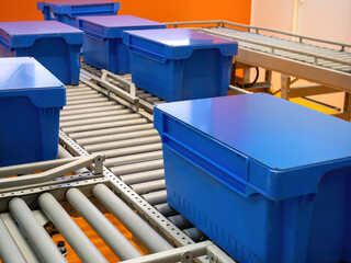 Poster - Manufactory technology. Conveyor with blue boxes. Modern manufactory inside. Production conveyor with packed goods. Equipment for manufactory. Blue plastic boxes are moving along production line