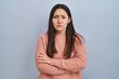 © Krakenimages.com - Young latin woman standing over blue background skeptic and nervous, disapproving expression on face with crossed arms. negative person.