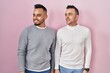 © Krakenimages.com - Homosexual couple standing over pink background looking away to side with smile on face, natural expression. laughing confident.