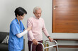 © tonefotografia - Asian nurse taking care of an elderly man with walker at senior healthcare center.